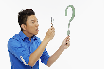 Man holding a magnifying glass up to a question mark