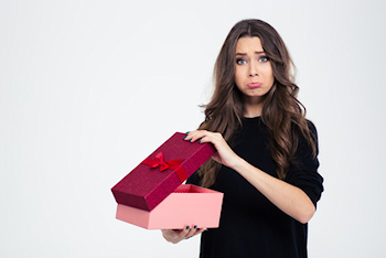 Woman holding gift and making sad face